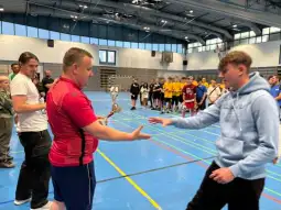Wręczenie trofeum podczas zawodów sportowych w hali.