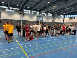 Grupa młodych ludzi w hali sportowej, przygotowujących się do zajęć.