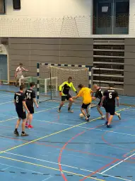 Mężczyźni grają w halową piłkę nożną w sportowej hali.