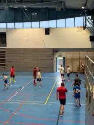 Młodzież grająca w piłkę nożną w hali sportowej.