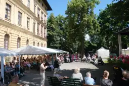 Spotkanie osób starszych na świeżym powietrzu, zorganizowane pod zadaszeniem w parku.