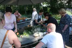 Warsztat florystyczny z uczestnikami tworzącymi bukiety z kwiatów.