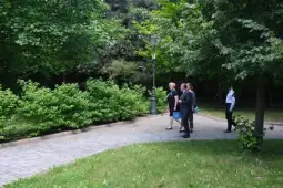 Grupa ludzi spacerujących po parku w otoczeniu zieleni.