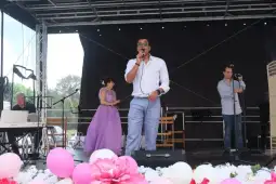 Mężczyzna śpiewa na scenie, obok niego kobieta w fioletowej sukni i dwóch muzyków.