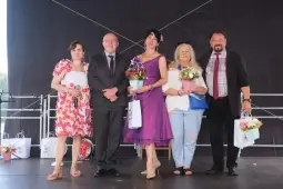 Grupa pięciu osób na scenie, każda trzyma bukiety kwiatów.