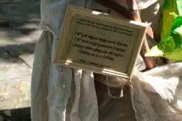 Tablica z tekstem o miejscu i perspektywie, zawieszona na postaci w naturalnym otoczeniu.