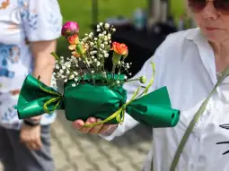 Bukiet kwiatów w zielonym opakowaniu z wstążką.
