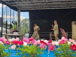 Występ artystyczny na scenie z kwiatową dekoracją i muzyką na żywo.