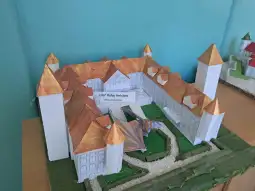 Model pałacu z papieru z wieżami i ogrodem.