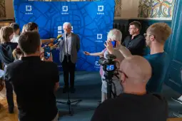 Konferencja prasowa w Krakowie z udziałem mężczyzny przy mikrofonie i dziennikarzy.