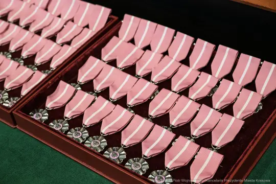 Zestaw medali z różowymi wstążkami ułożony w eleganckim pudełku.