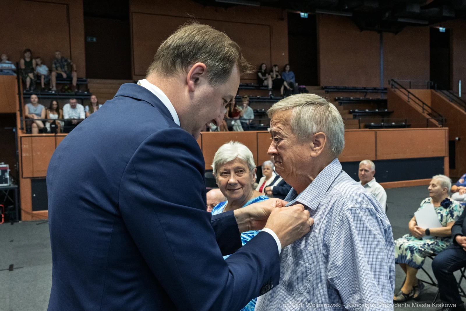 Wręczenie odznaczenia mężczyźnie przez uśmiechniętego mężczyznę w formalnym stroju.  Autor: Piotr Wojnarowski