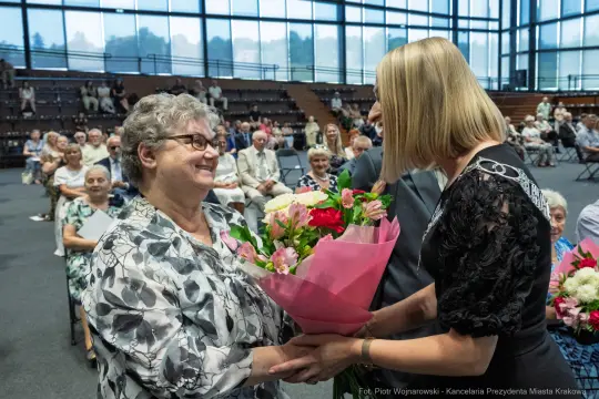 Uroczystość wręczenia kwiatów kobiecie w towarzystwie zgromadzonych gości.