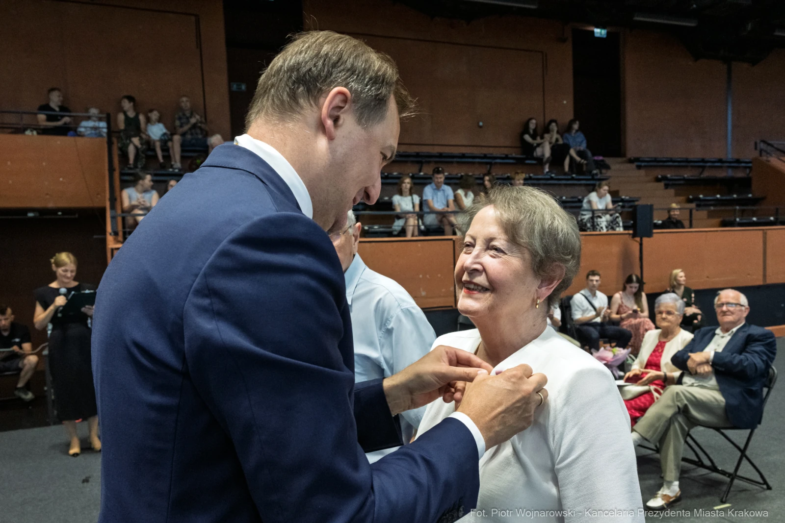 Wręczenie odznaczenia przez mężczyznę starszej kobiecie podczas uroczystości.  Autor: Piotr Wojnarowski