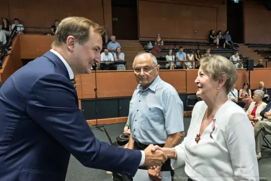 Spotkanie mężczyzny w garniturze z dwojgiem starszych ludzi, uściski dłoni i uśmiechy.