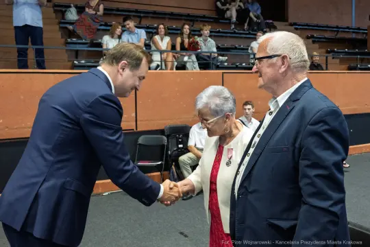 Uścisk dłoni między mężczyzną a starszą parą w sali.