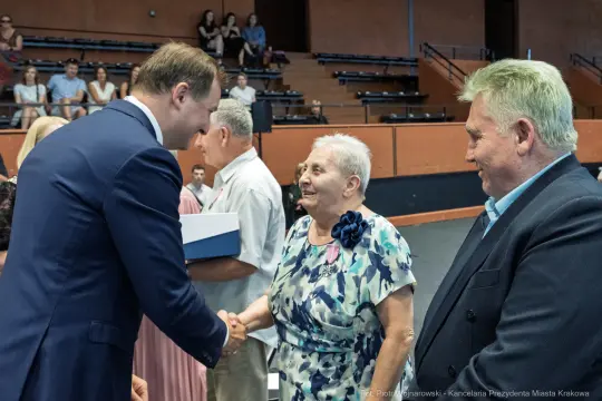 Uroczystość wręczenia nagród, uściski dłoni i uśmiechy uczestników.