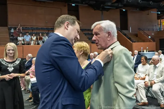 Wręczenie odznaczenia mężczyźnie podczas uroczystości w sali.