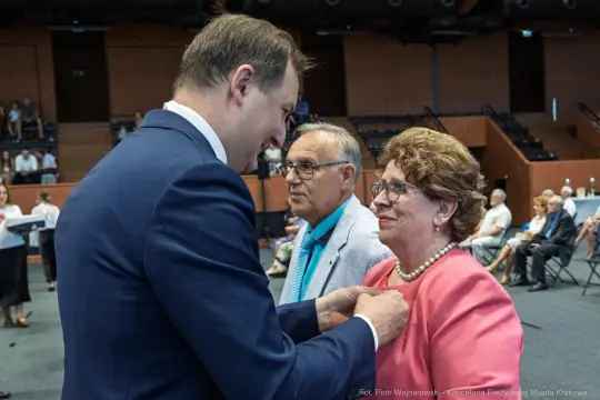 Wręczenie odznaczenia przez mężczyznę kobiecie w towarzystwie drugiego mężczyzny.