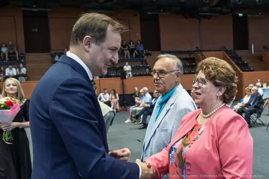 Spotkanie mężczyzny w garniturze z parą starszych osób, wręczenie kwiatów.