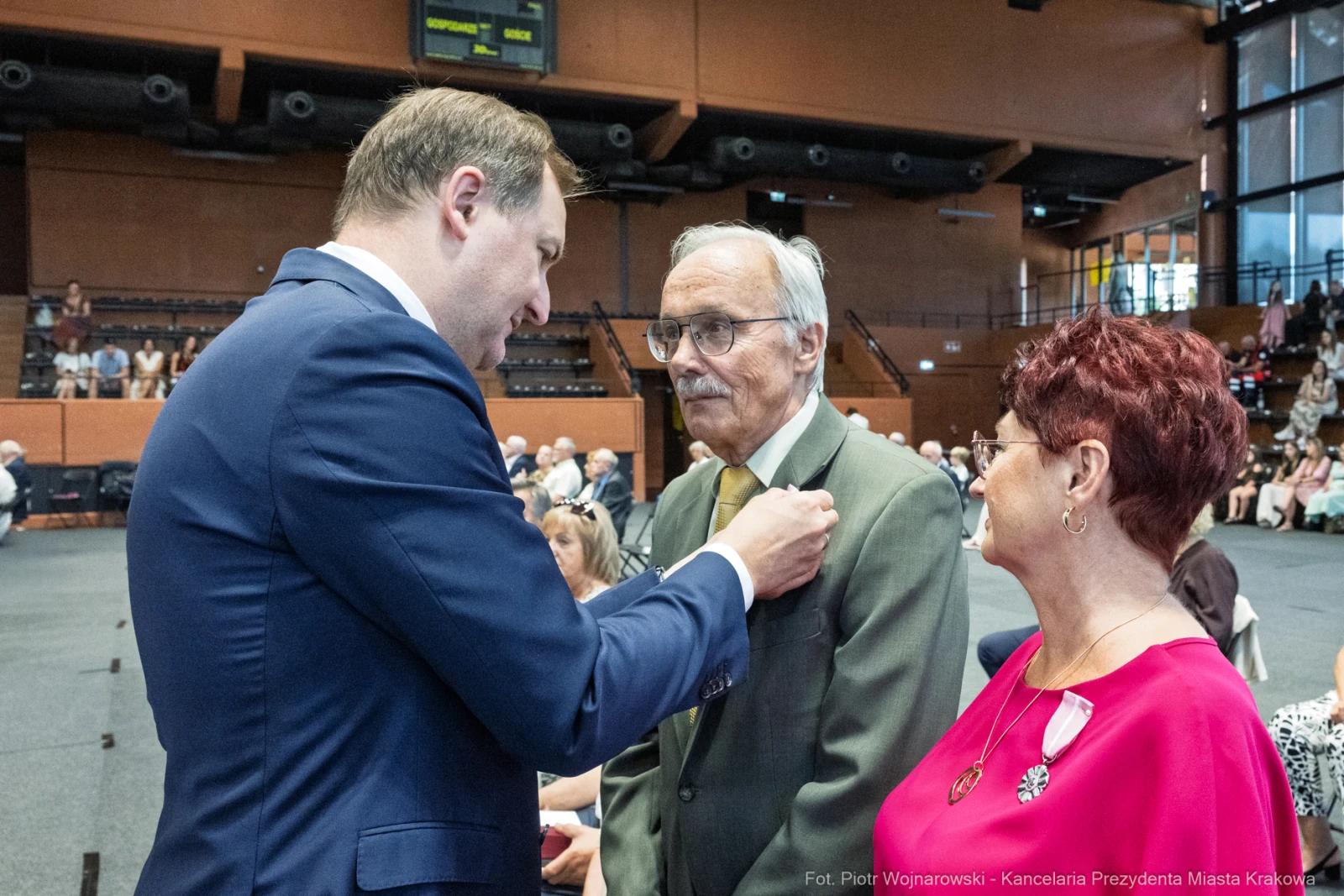 Uroczystość wręczenia odznaczeń, mężczyzna rozmawia z odznaczonymi.  Autor: Piotr Wojnarowski