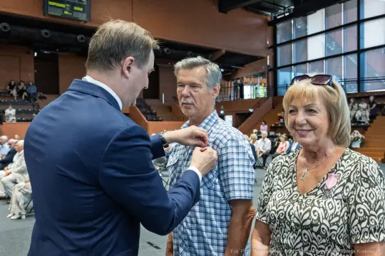 Uroczystość wręczenia odznaczeń, mężczyzna otrzymuje medal od oficjela.