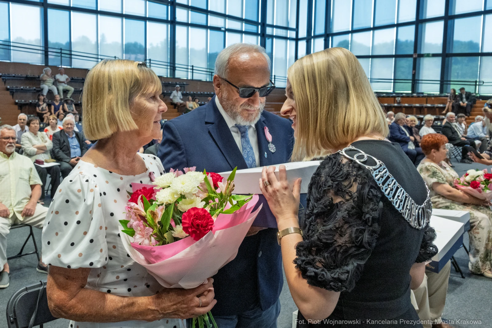 Uroczystość wręczenia nagród, osoby z kwiatami i w okularach przeciwsłonecznych.  Autor: Piotr Wojnarowski