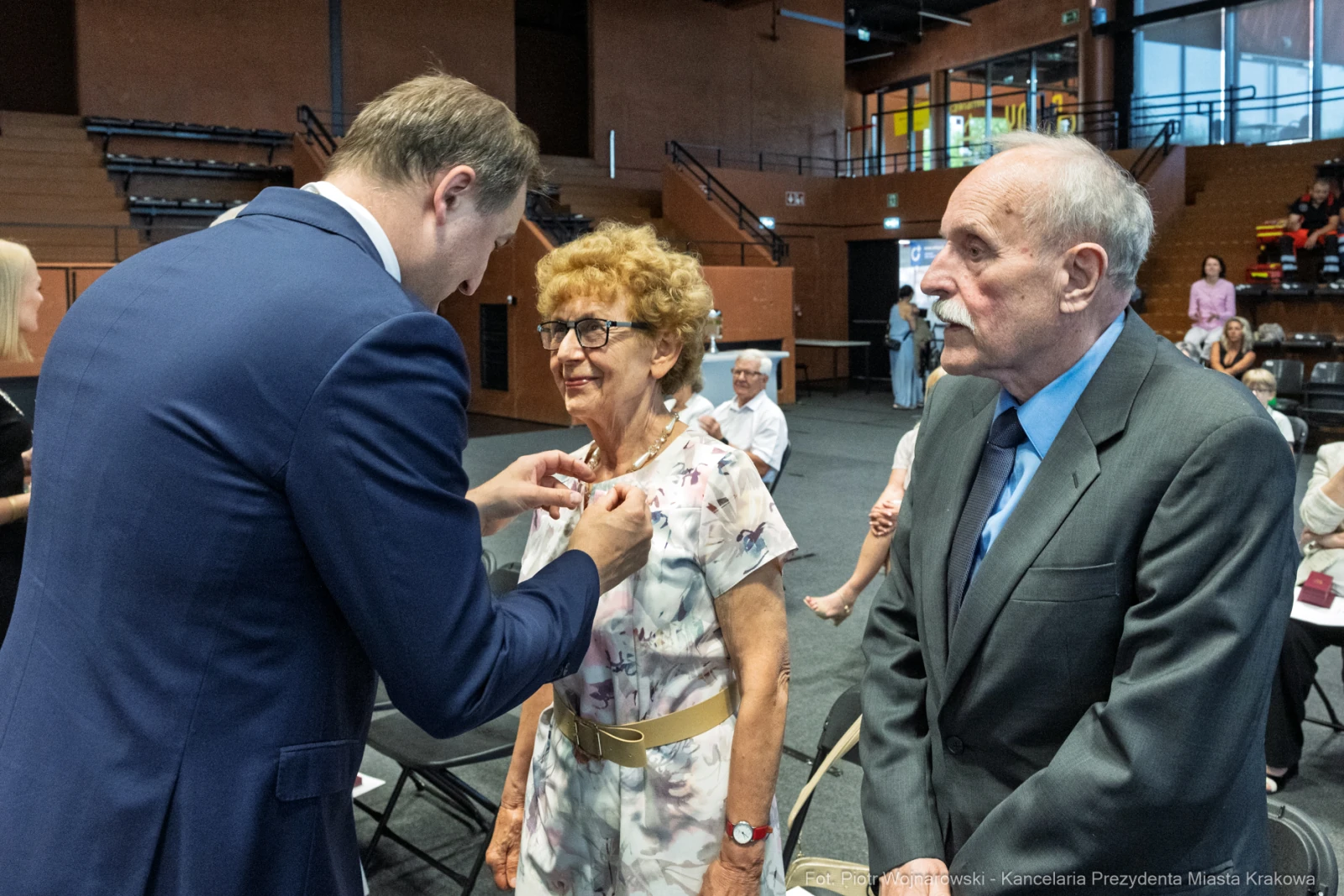 Wręczenie odznaczenia kobiecie przez mężczyznę, w tle zgromadzenie osób.  Autor: Piotr Wojnarowski