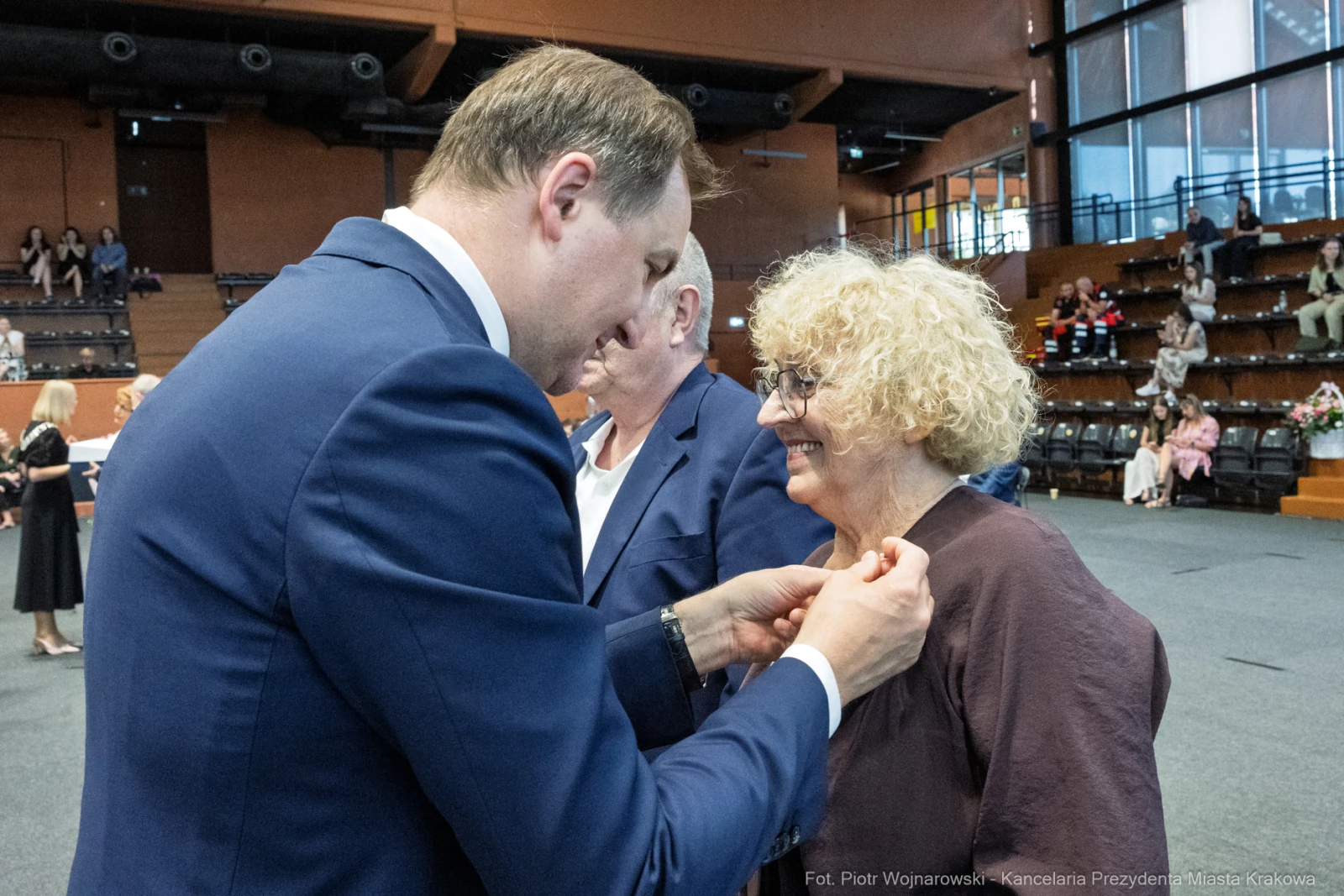 Wręczenie odznaczenia przez mężczyznę kobiecie podczas uroczystości.  Autor: Piotr Wojnarowski