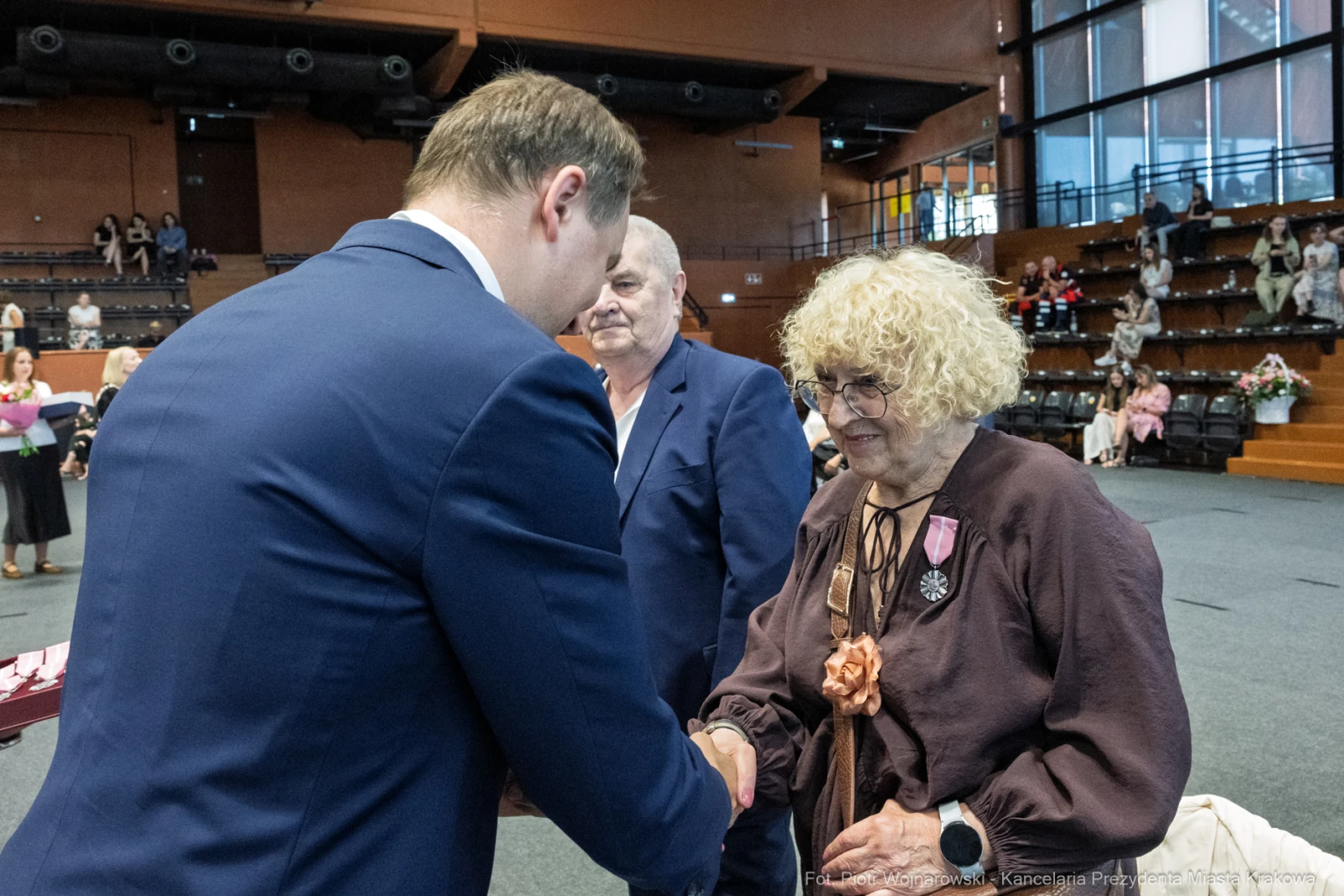 Uroczystość wręczenia odznaczeń, starsza kobieta w rozmowie z mężczyzną w garniturze.  Autor: Piotr Wojnarowski
