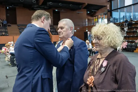 Uroczystość wręczenia odznaczeń, mężczyzna otrzymuje medal od innej osoby.