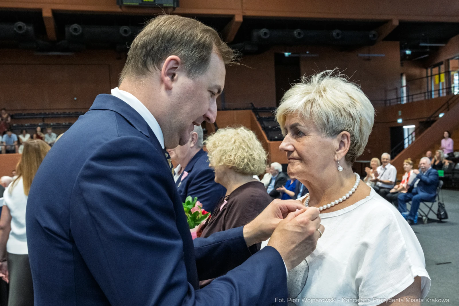Uroczystość wręczenia odznaczeń, mężczyzna przypina medal kobiecie.  Autor: Piotr Wojnarowski