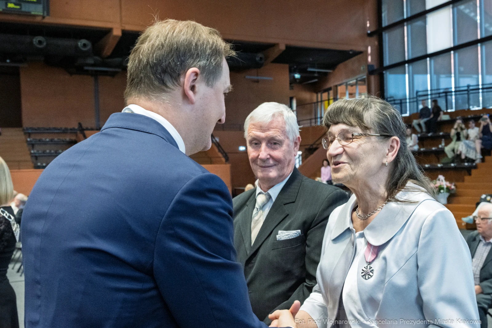 Spotkanie trzech osób w eleganckich strojach, rozmowa w formalnej atmosferze.  Autor: Piotr Wojnarowski