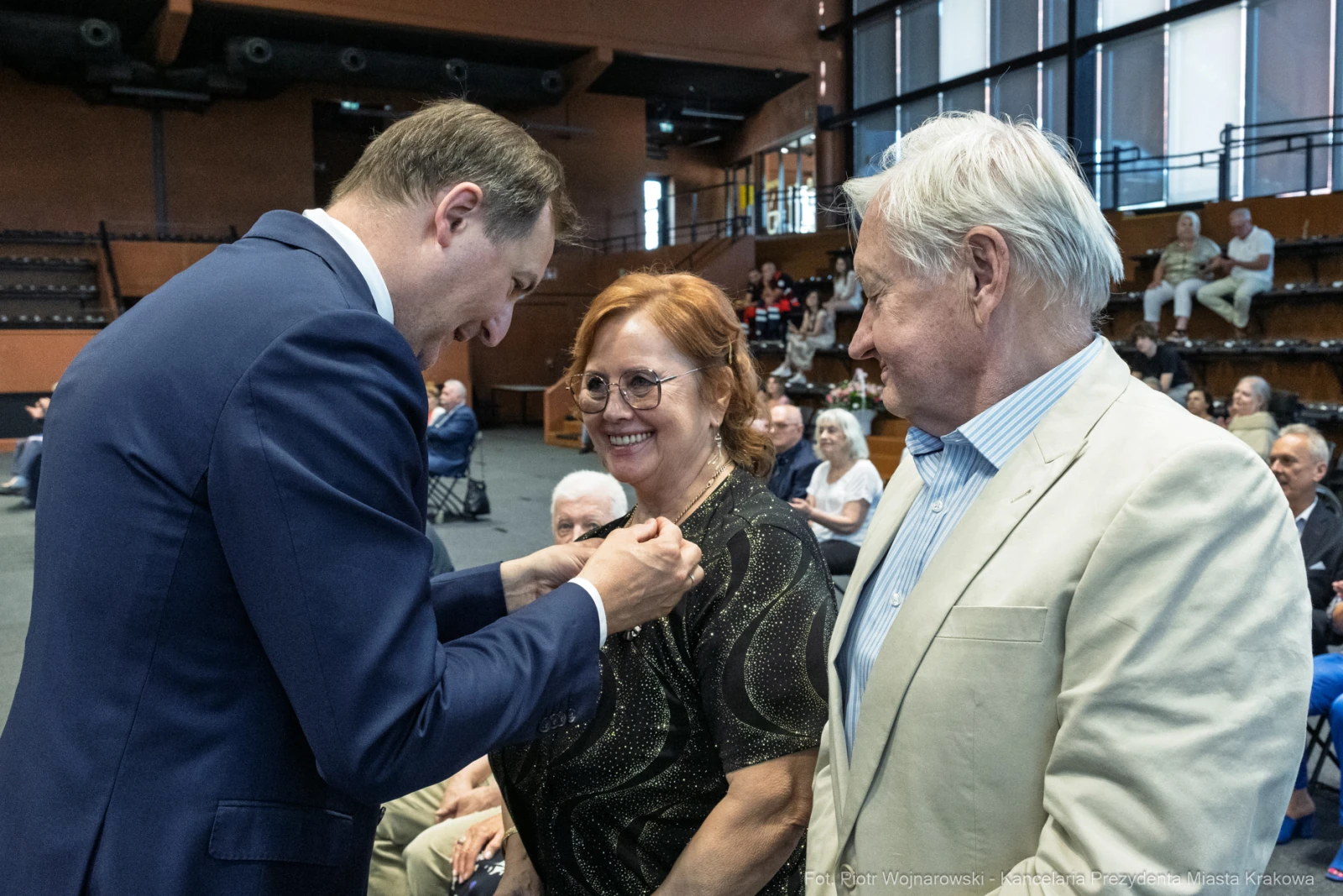 Uroczystość wręczenia odznaczenia dwóm osobom w towarzystwie zgromadzonej publiczności.  Autor: Piotr Wojnarowski