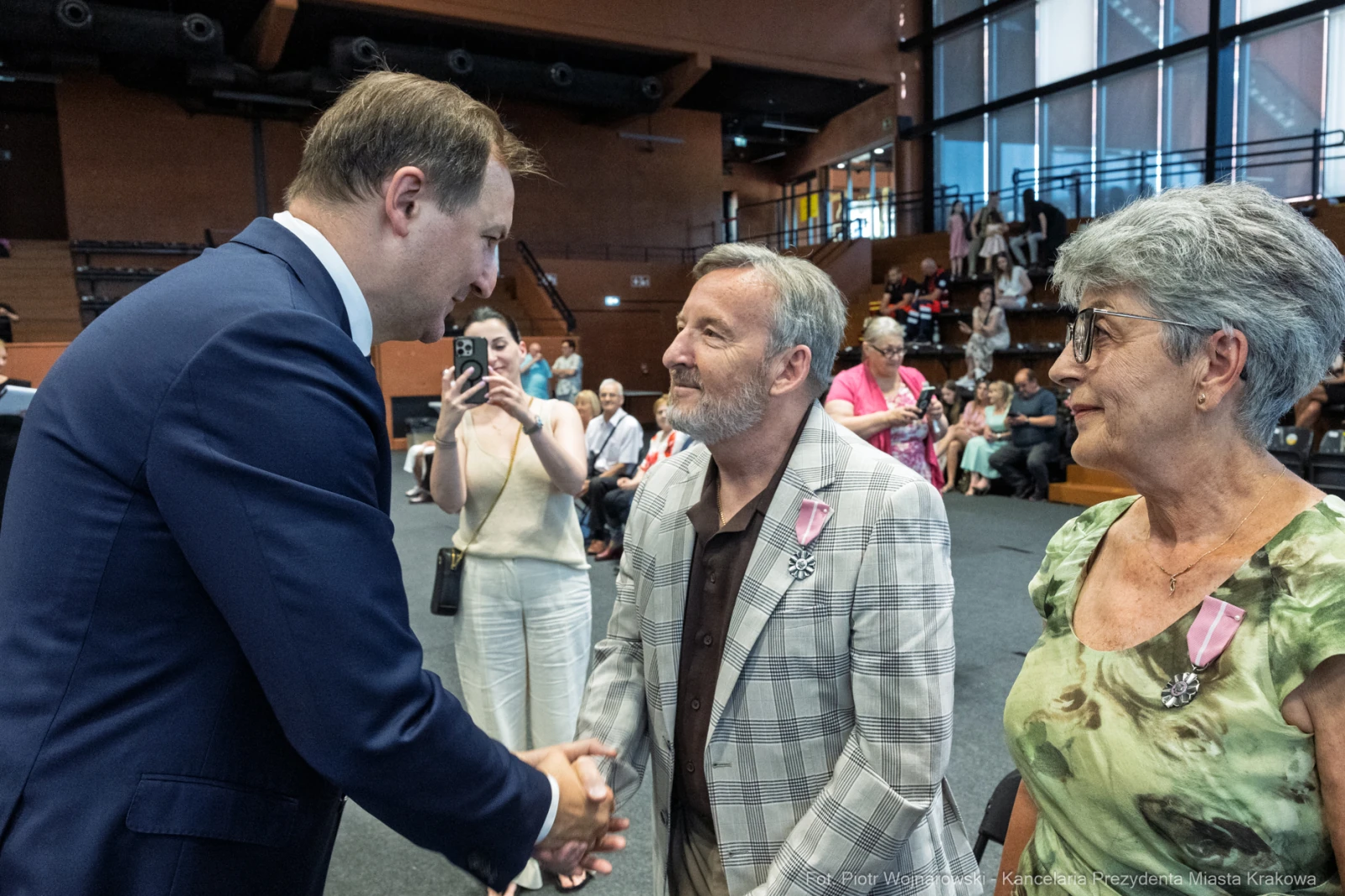 Spotkanie trzech osób, w tym mężczyzny w garniturze, w sali z widownią.  Autor: Piotr Wojnarowski