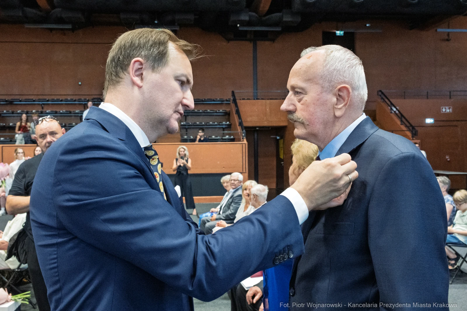 Mężczyzna przypina odznaczenie innemu mężczyźnie podczas uroczystości.  Autor: Piotr Wojnarowski