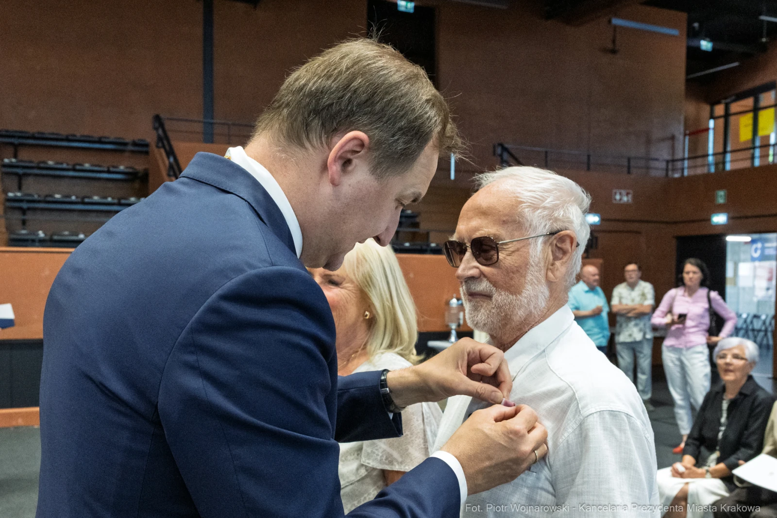 Mężczyzna przypina odznaczenie starszemu mężczyźnie w trakcie uroczystości.  Autor: Piotr Wojnarowski