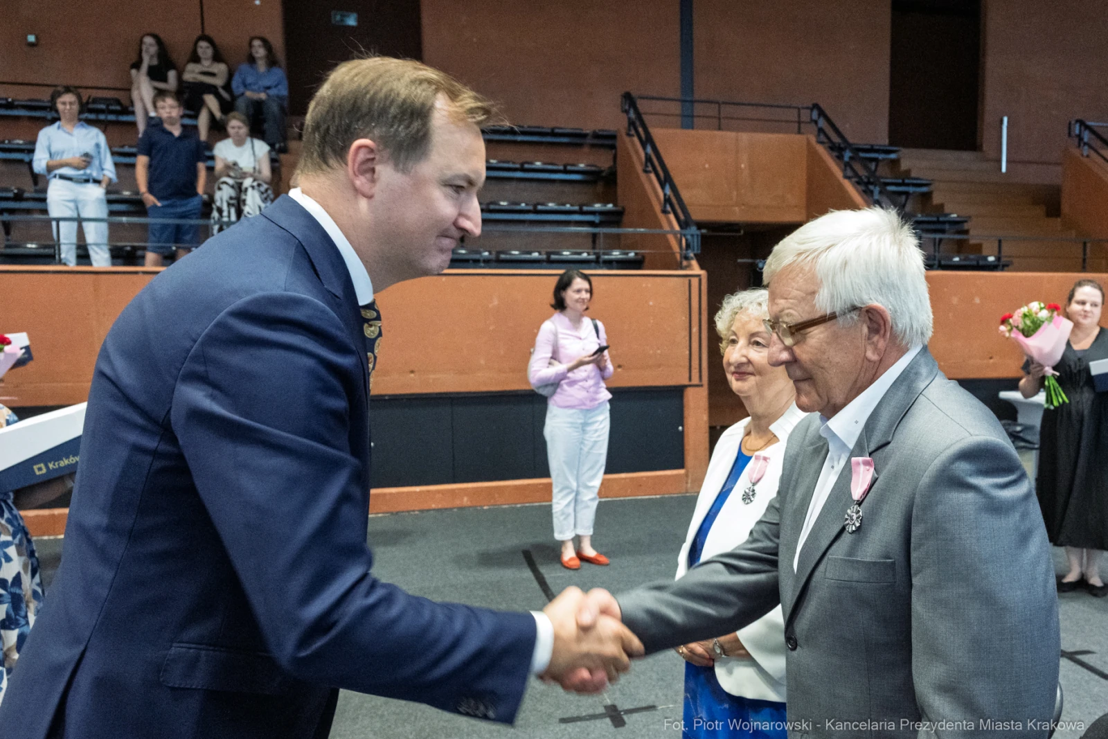 Uroczystość wręczenia odznaczeń, mężczyzna podaje rękę starszemu mężczyźnie.  Autor: Piotr Wojnarowski