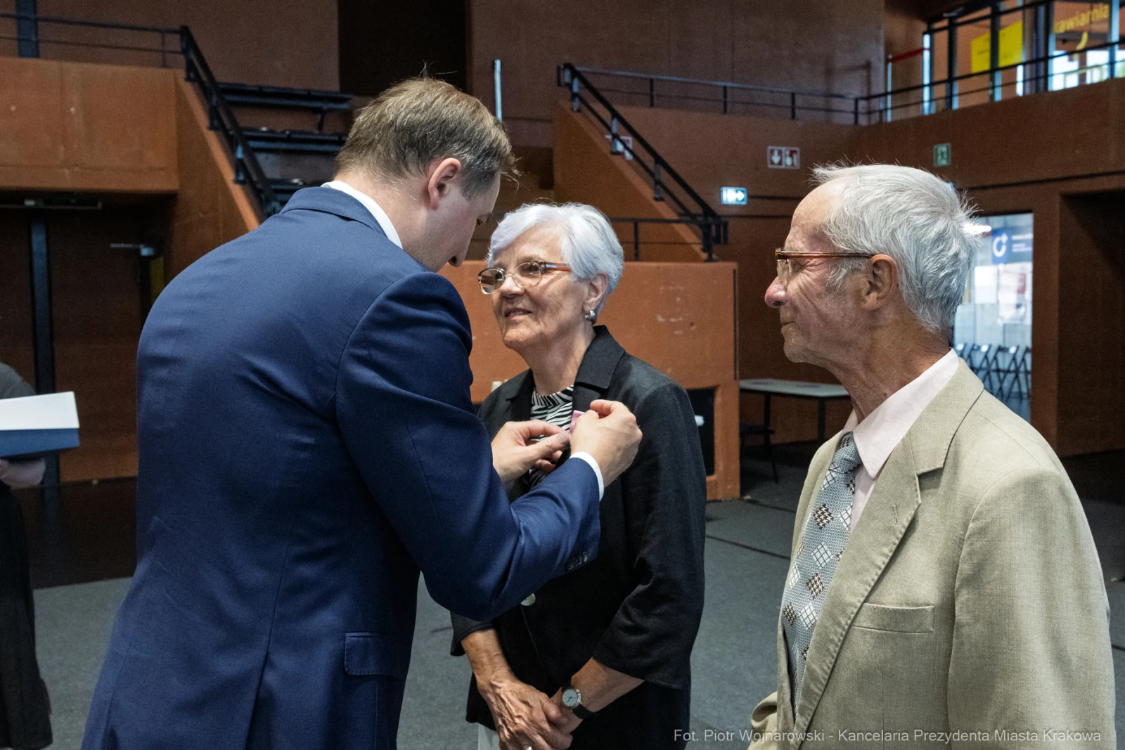Wręczenie odznaczenia starszej parze przez mężczyznę w garniturze.  Autor: Piotr Wojnarowski