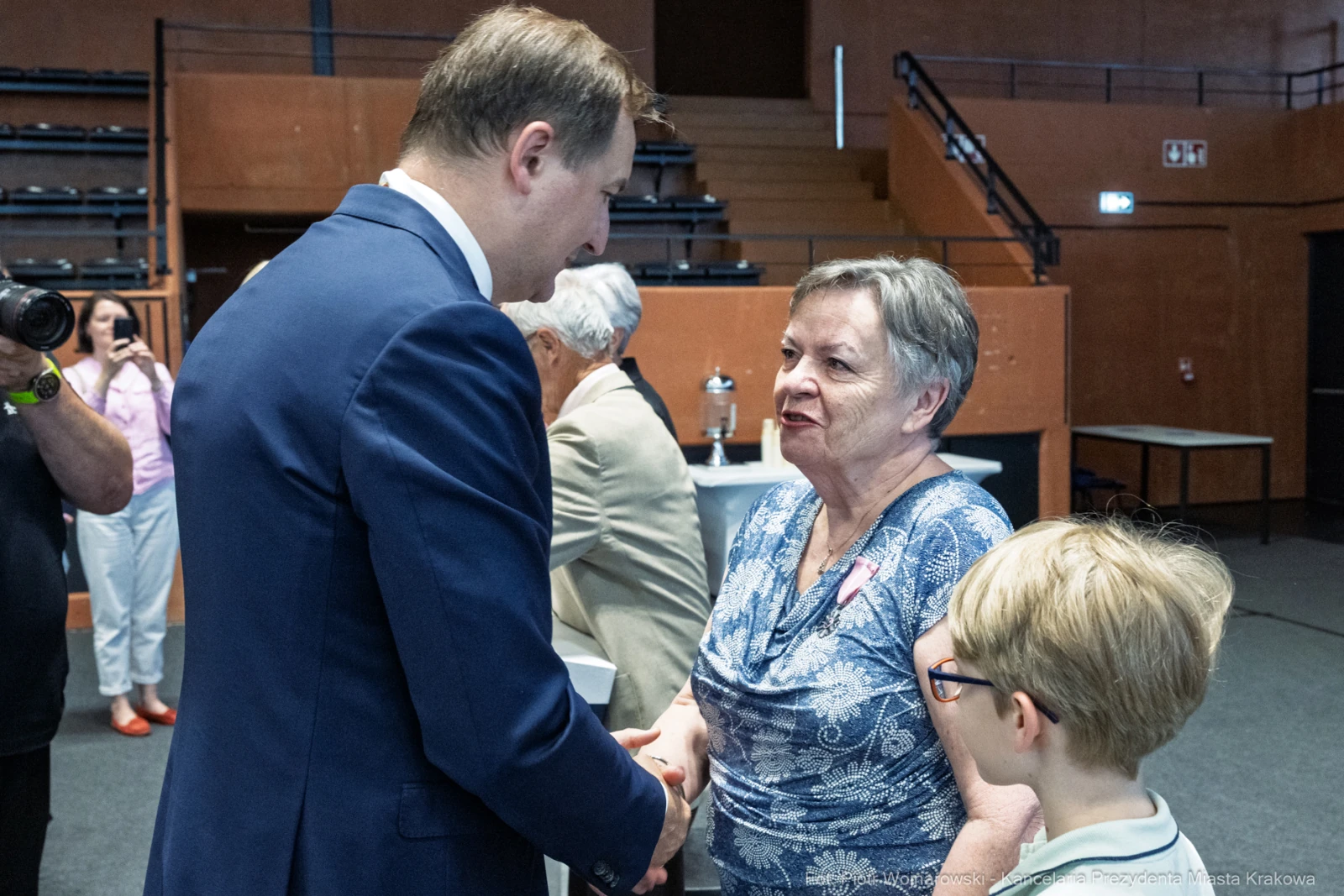 Spotkanie dwóch osób, jedna z nich uścisnęła dłoń drugiej, w tle widoczni inni uczestnicy.  Autor: Piotr Wojnarowski