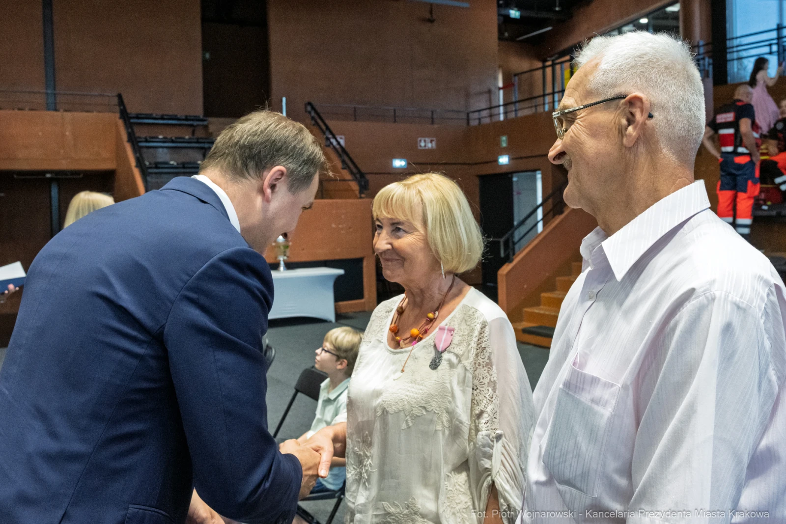 Uścisk dłoni między mężczyzną a kobietą, w tle widoczni inni uczestnicy wydarzenia.  Autor: Piotr Wojnarowski