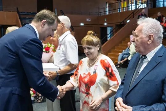 Uroczystość wręczenia nagród, uściski dłoni i kwiaty.
