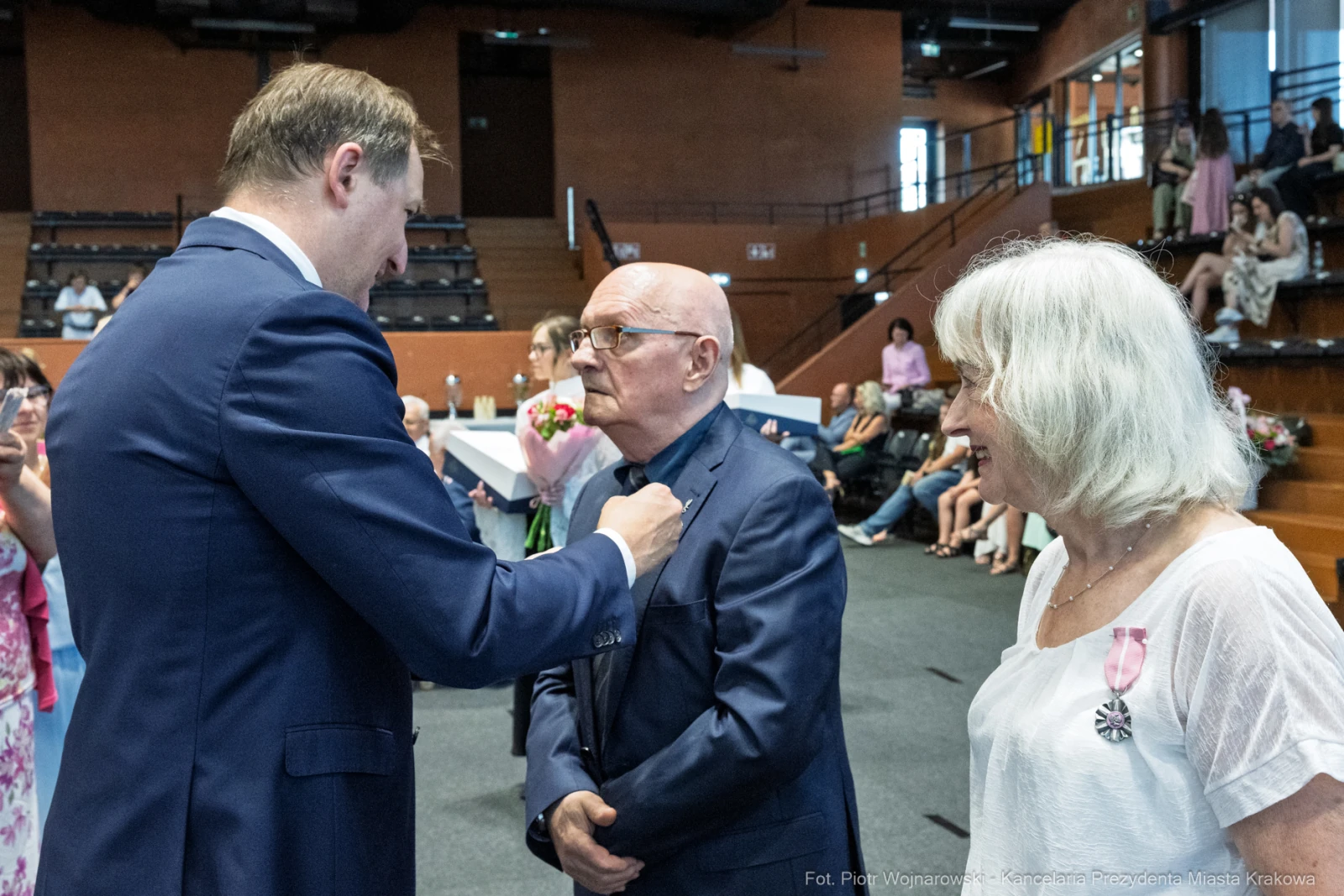 Uroczystość wręczenia odznaczeń, mężczyzna w garniturze rozmawia z odznaczonym.  Autor: Piotr Wojnarowski