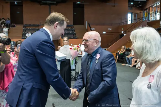 Uroczystość wręczenia odznaczeń, gratulacje i uściski dłoni.