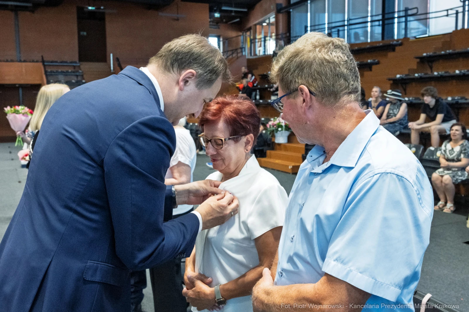 Wręczenie odznaczenia przez mężczyznę kobiecie w obecności innego mężczyzny.  Autor: Piotr Wojnarowski