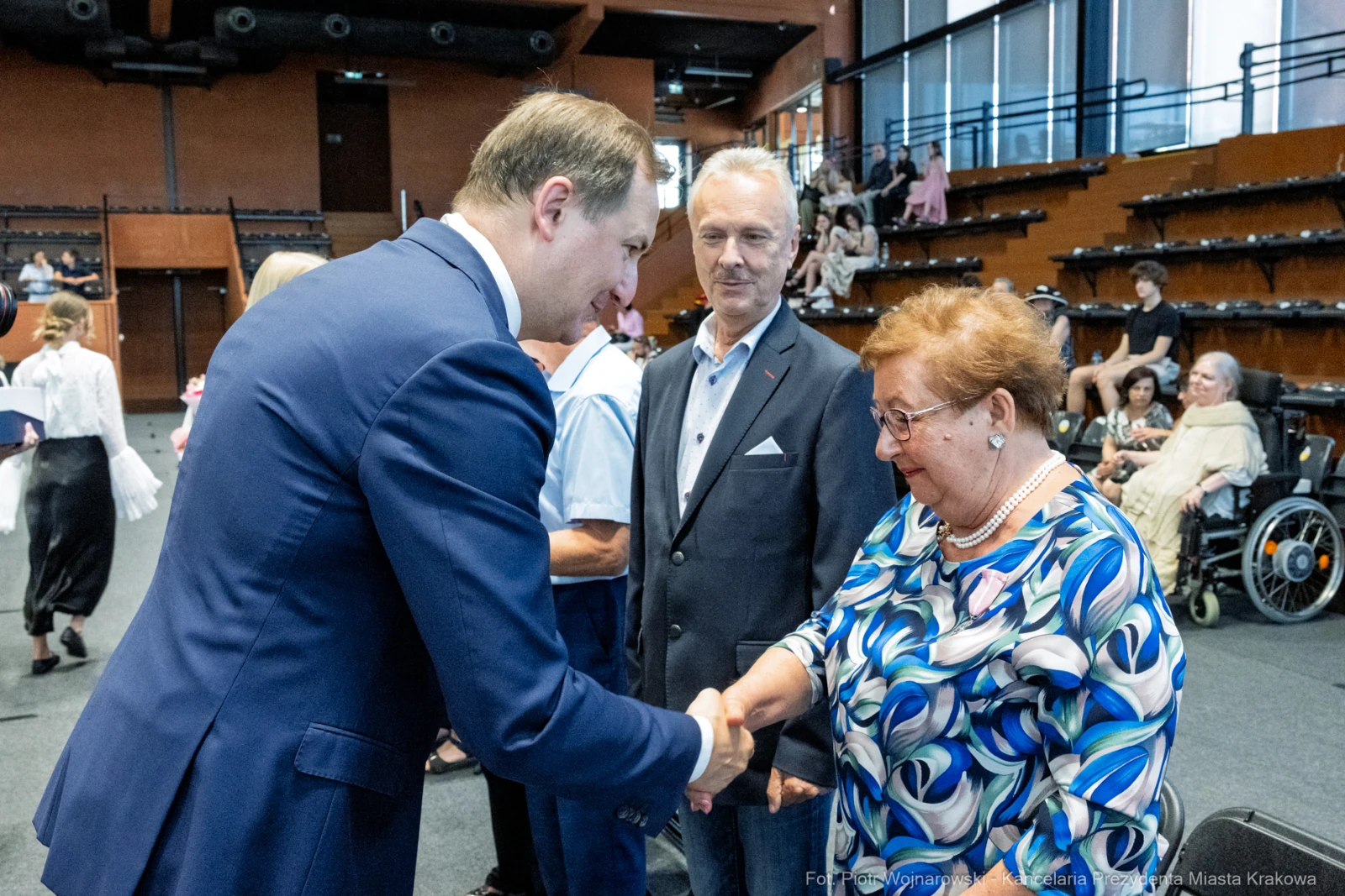 Uścisk dłoni między mężczyzną a kobietą, w tle widoczni inni uczestnicy wydarzenia.  Autor: Piotr Wojnarowski