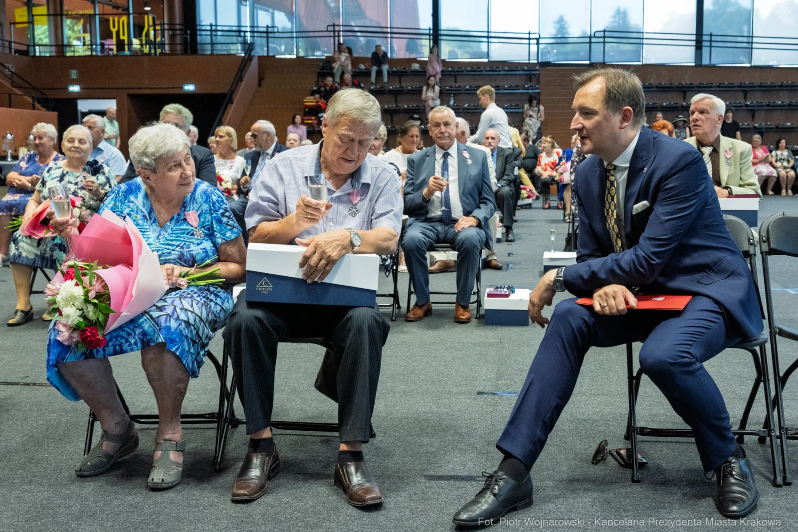Uczestnicy uroczystości siedzący na widowni, z kwiatami i upominkami.  Autor: Piotr Wojnarowski