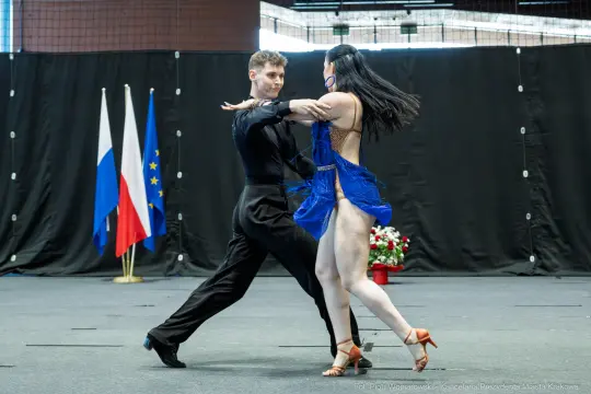 Para tańcząca w rytm muzyki, w tle flagi Rosji i Unii Europejskiej.