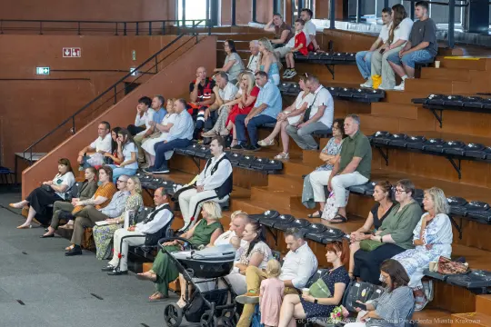 Grupa ludzi siedzących na widowni w sali konferencyjnej.