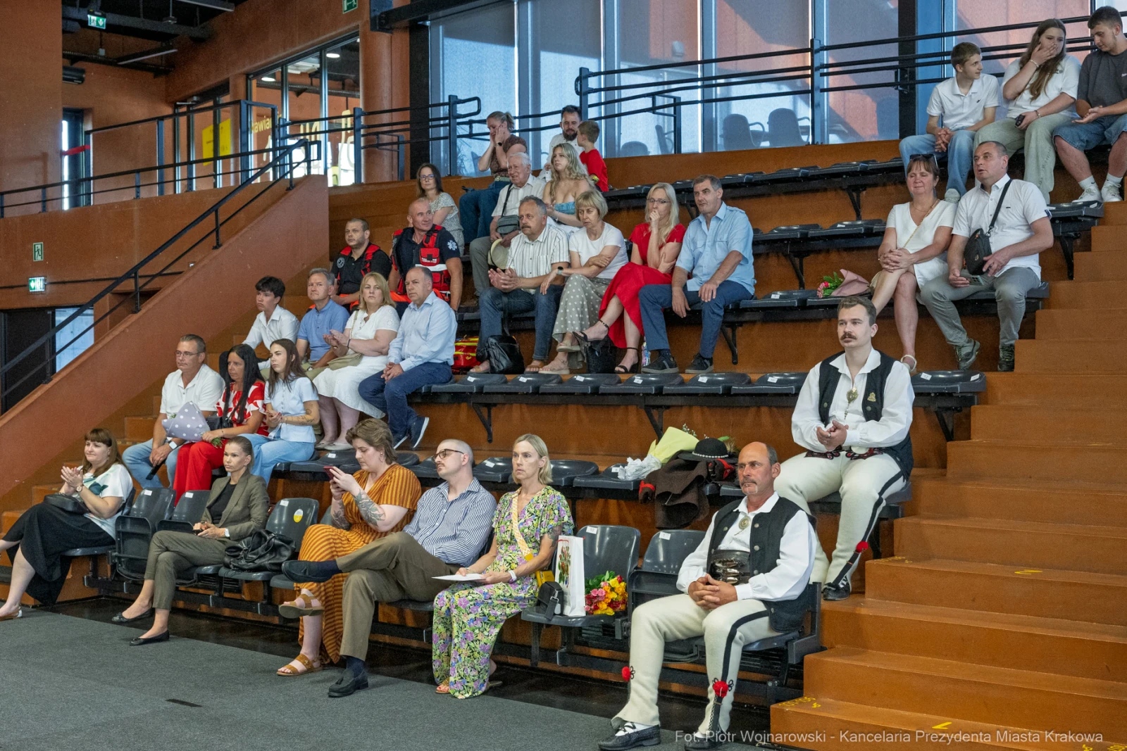 Grupa ludzi siedzących na widowni w sali, część w strojach regionalnych.  Autor: Piotr Wojnarowski